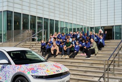 School children sitting on a staircase with a Hyundai Ioniq 5 in the foreground.