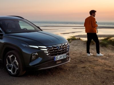 Imagen de un joven mirando al horizonte con un Hyundai junto a él