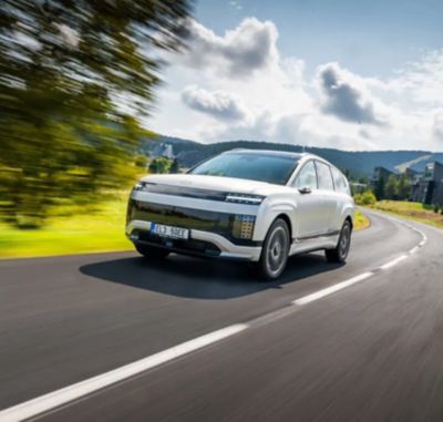 IONIQ 9 projíždějící po okresní cestě.