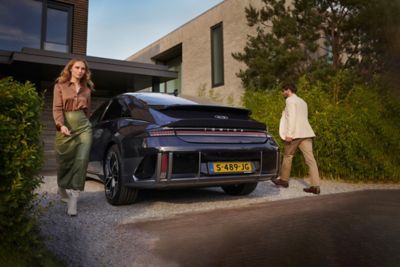 woman with brown t-shirt and a man standing next to the Hyundai IONIQ 6 