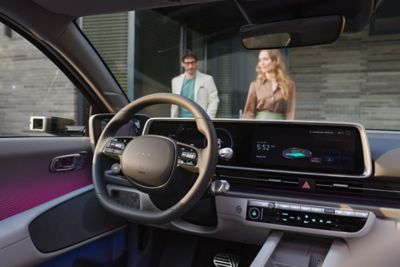 Blick aus dem Innenraum eines Hyundai IONIQ 6 durch die Frontscheibe, vor dem Fahrzeug stehen ein Mann und eine Frau.