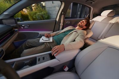 man with white suit and green t-shirt is laying on the 8-way adjustable seat of the Hyundai IONIQ 6