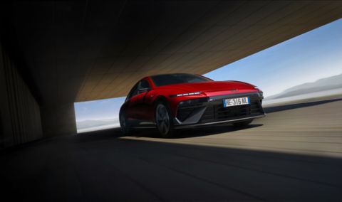 Hyundai IONIQ 6 electric sedan shown from the side parked on a city street with high rise buildings.