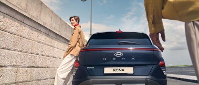 Portón trasero del Hyundai KONA abriéndose automáticamente para que una mujer pueda meter sus cajas.