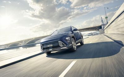 Una Hyundai KONA percorre una strada cittadina.