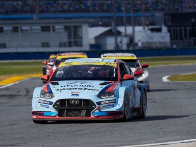  A picture of Hyundai Motorsport customer racing Veloster N TCR in action on a racetrack shown from the side