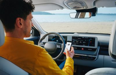 Hombre en el asiento del conductor del Hyundai IONIQ 5, consultando su aplicación myHyundai.