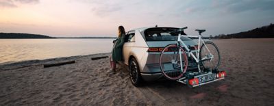 Hyundai IONIQ 5 with bike rack parked on the beach during sunset.