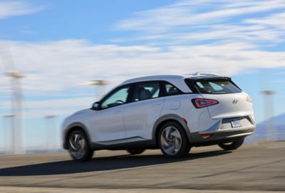 Imagen del Hyundai NEXO y una mujer frente a las vistas de una ciudad.