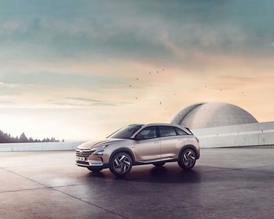 Vue latérale de Hyundai NEXO au crépuscule, devant un bâtiment futuriste.