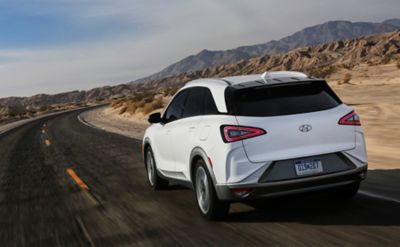 Imagen del Hyundai NEXO y una mujer frente a las vistas de una ciudad.