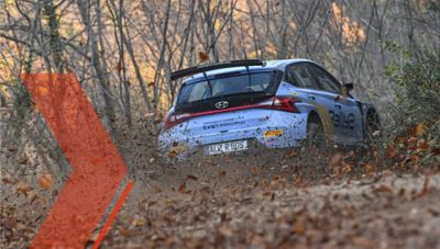 Hyundai Motorsport customer racing a Hyundai i20 N Rally2 car on a dirt road covered in leaves