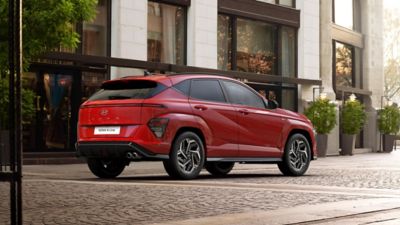 The all-new KONA N Line S in red is parked next to a modern building.