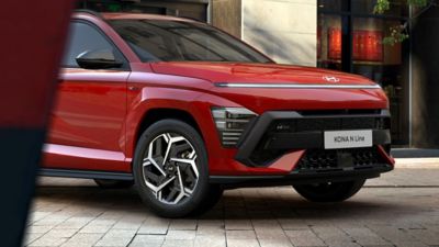 The all-new Hyundai KONA N Line S in red parked in front of an architecture building. 