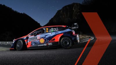 Samochód rajdowy Hyundai i20 N WRC pokonuje ostry zakręt na nocnej trasie.