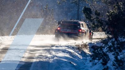 Samochód rajdowy Hyundai i20 N WRC pokonuje ostry zakręt podczas zimowego wyścigu.