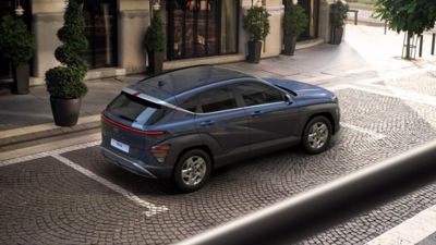 The all-new Hyundai KONA N Line parked in the city with a woman standing next to it.