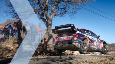 Hyundai i20 N WRC Rally1 skaczący na drodze podczas rajdu.