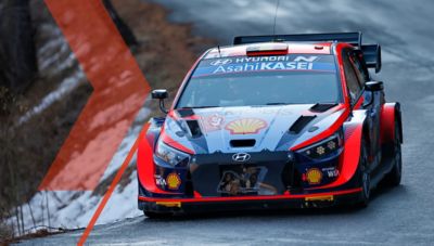 Samochód rajdowy Hyundai i20 N WRC pokonuje ostry zakręt podczas zimowego wyścigu.