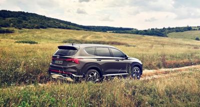 Hyundai KONA Elektrik SUV’un gün ışığı altında görüntüsü ve yolcu kapısına doğru yürüyen bir bir adam. 