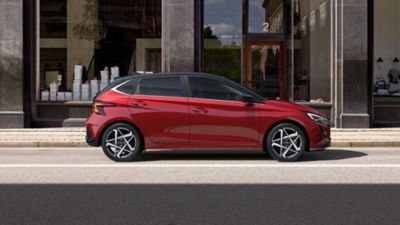 Hyundai i20 Dragon Red Pearl parked on the city street.