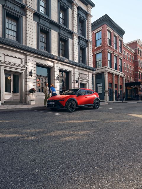 Red Hyundai IONIQ 3 shown from front three‑quarter angle on an urban street.