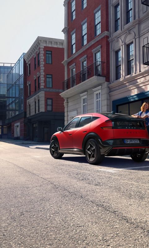 Red Hyundai IONIQ 3 shown from rear three‑quarter angle on an urban street.