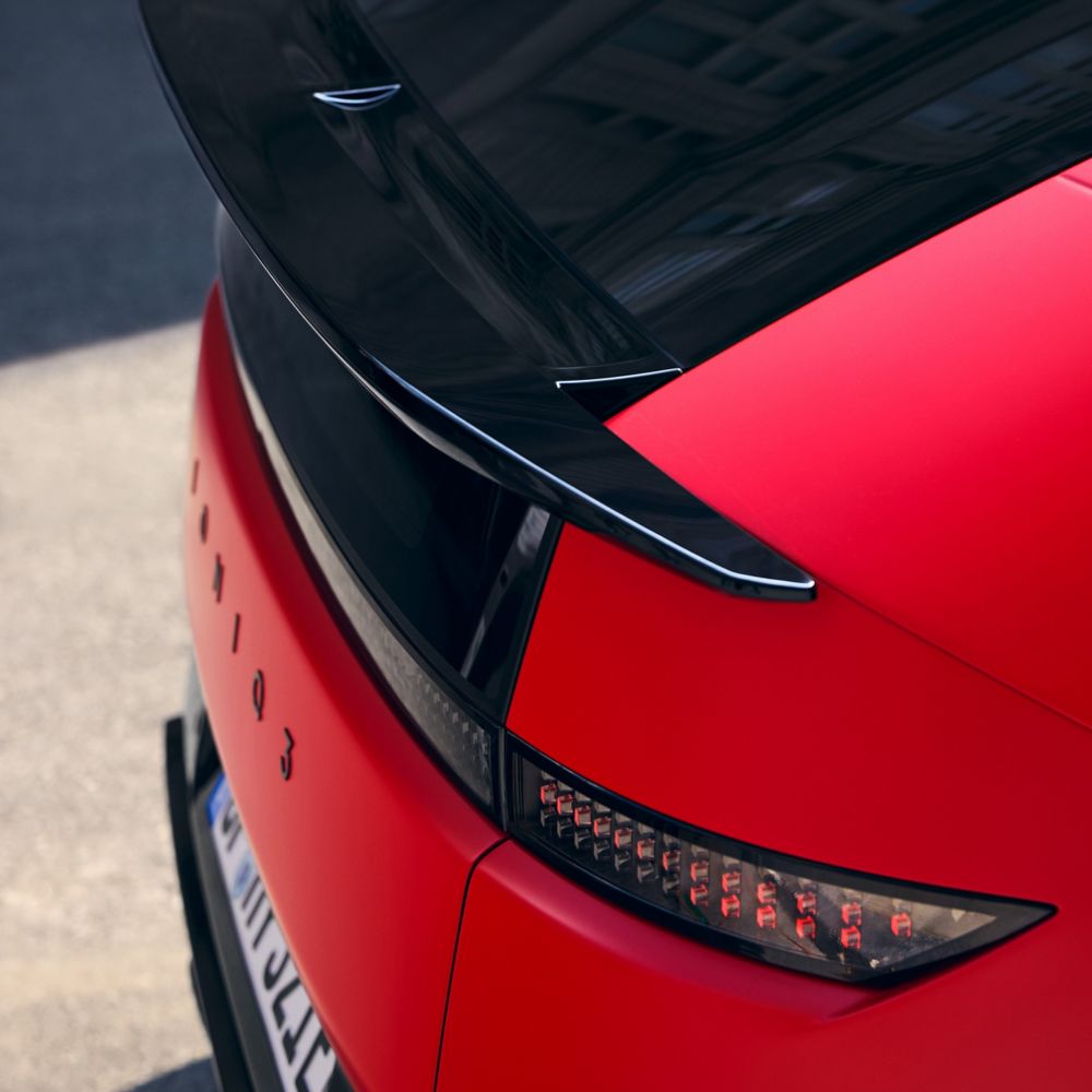 Detail zadní části červeného Hyundai IONIQ 3 s černým střešním spoilerem a pixelovým designem LED zadních světel.