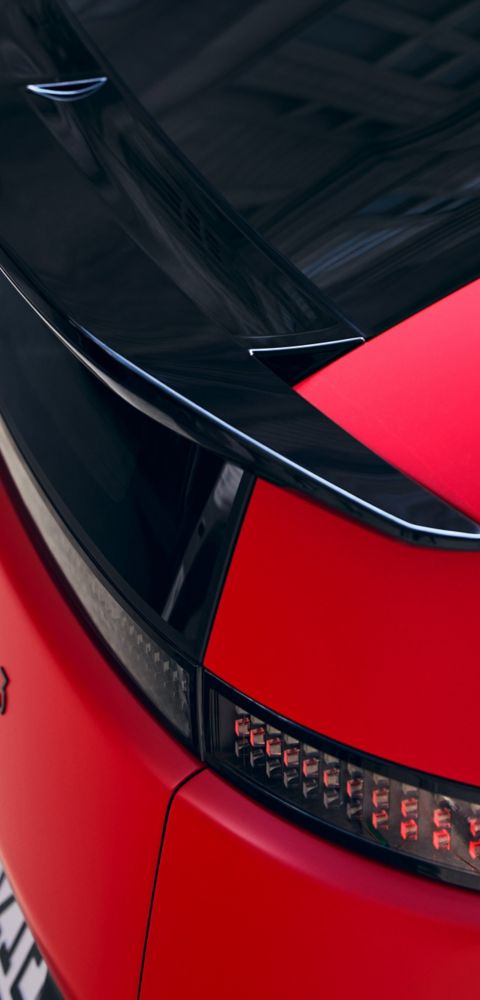 Red Hyundai IONIQ 3 rear detail with black roof spoiler and pixel-style LED taillight design.