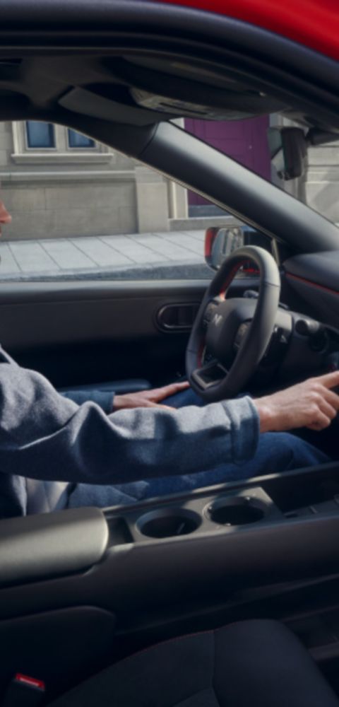 Black interior of a Hyundai IONIQ 3 with a central screen; a person seated in the front.