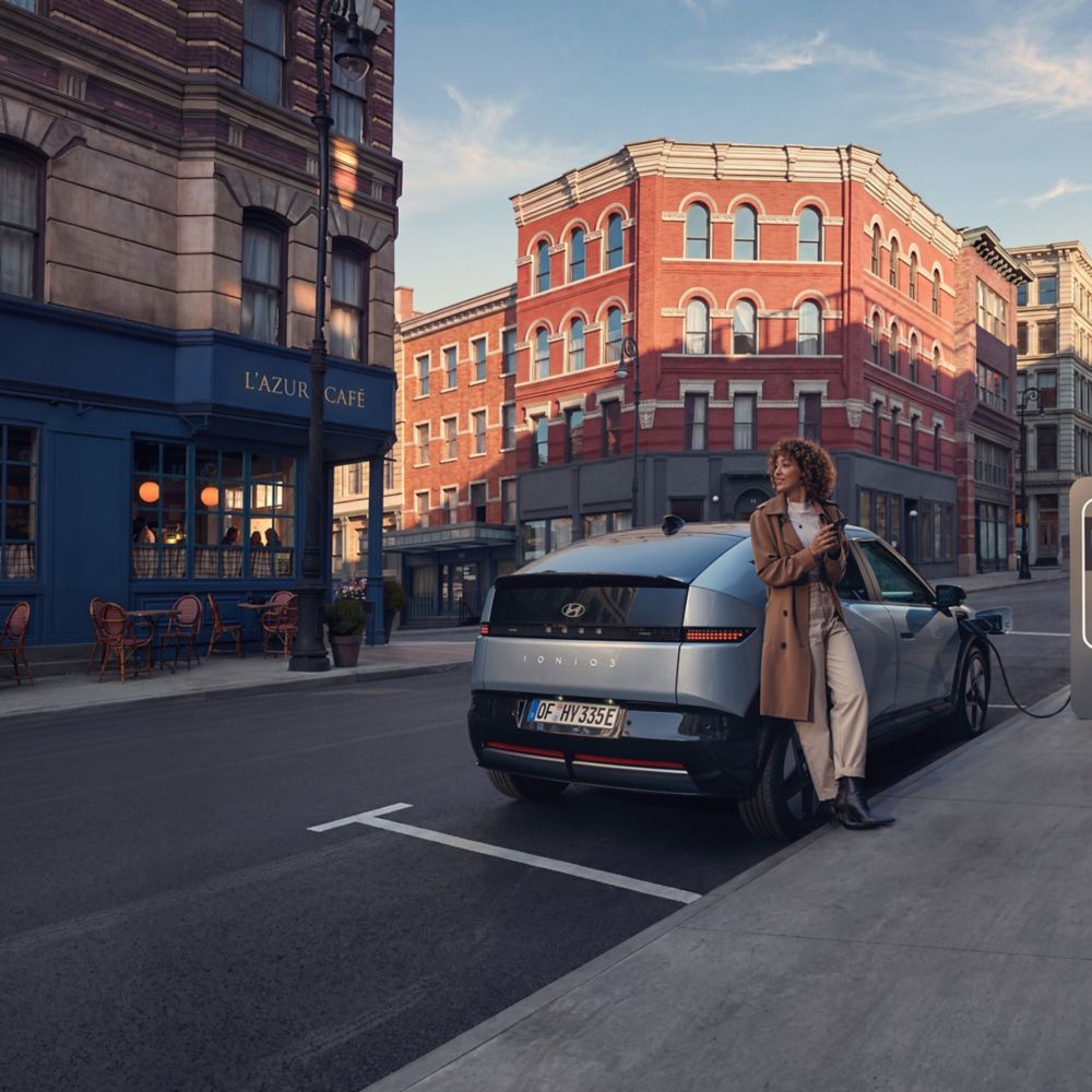 Hyundai IONIQ 3 laddas på en stadsgata med en person intill bilen.