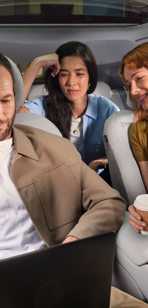 Tři lidé sedí v interiéru Hyundai IONIQ 3, zatímco jeden z nich pracuje na notebooku.