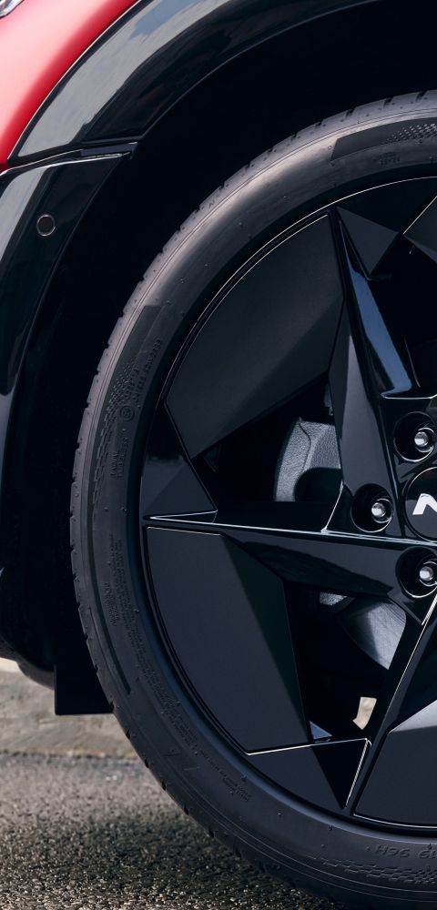 Wheel detail with black alloy rim featuring angular aero-inspired design.