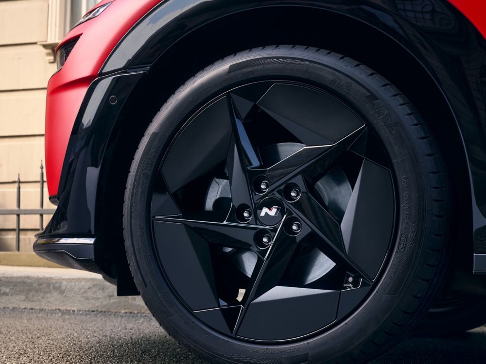 Wheel detail with black alloy rim featuring angular aero-inspired design.