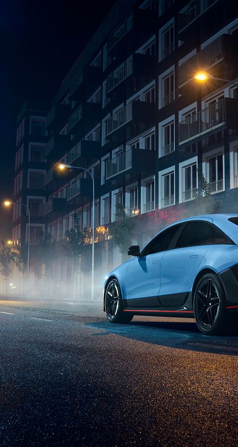 La IONIQ 6 N, illuminata di notte, parcheggiata su una strada cittadina, sottolinea il suo design raffinato.