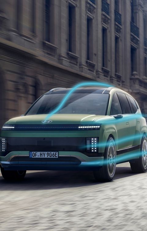 Hyundai IONIQ 9 driving through a city street with an aerodynamic flow graphic.