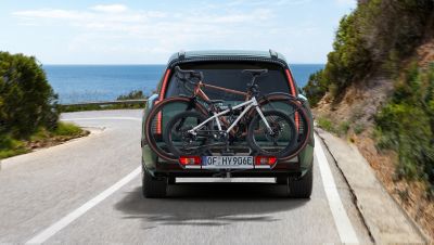 The IONIQ 9 driving down the road with bikes attached to the rear.