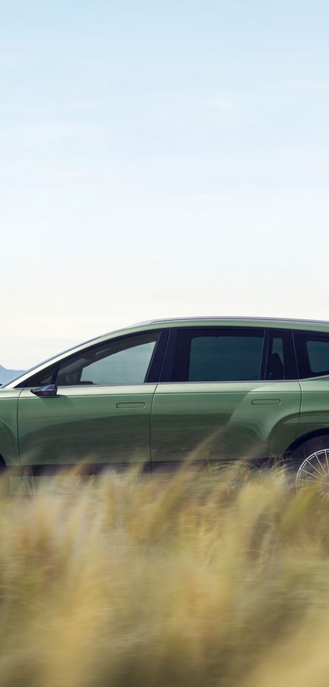 The side view of the IONIQ 9 driving around on a country road.