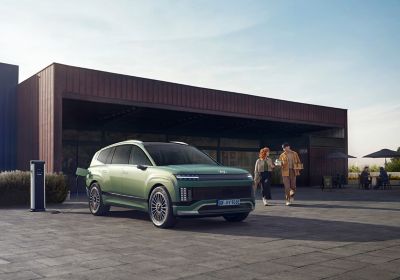 IONIQ 9 podłączony do ładowania przed budynkiem.