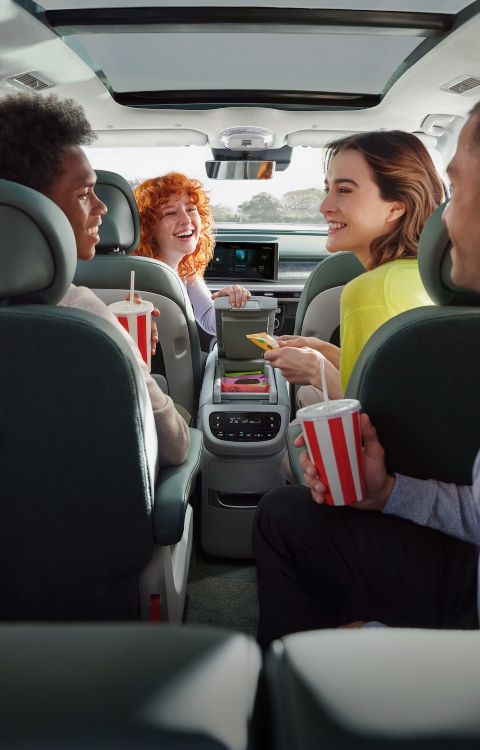 Four people in the Hyundai IONIQ 9 interior sharing snacks and drinks.