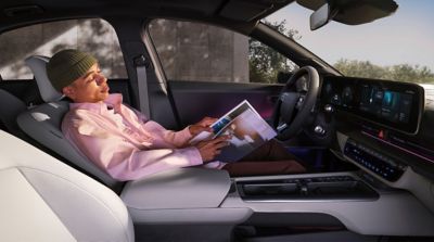 Homme allongé dans le siège relax de la rangée avant de la berline entièrement électrique Hyundai IONIQ 6.