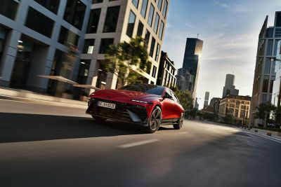Červený Hyundai IONIQ 6 N Line projíždí moderní městskou krajinou.