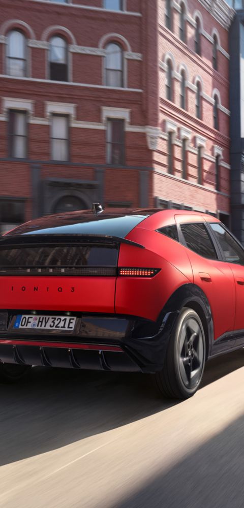 Hyundai IONIQ 3 rouge roulant dans une rue en milieu urbain.