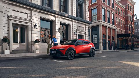 Man and Woman standing next to red Hyundai IONIQ 3 parked on an urban str