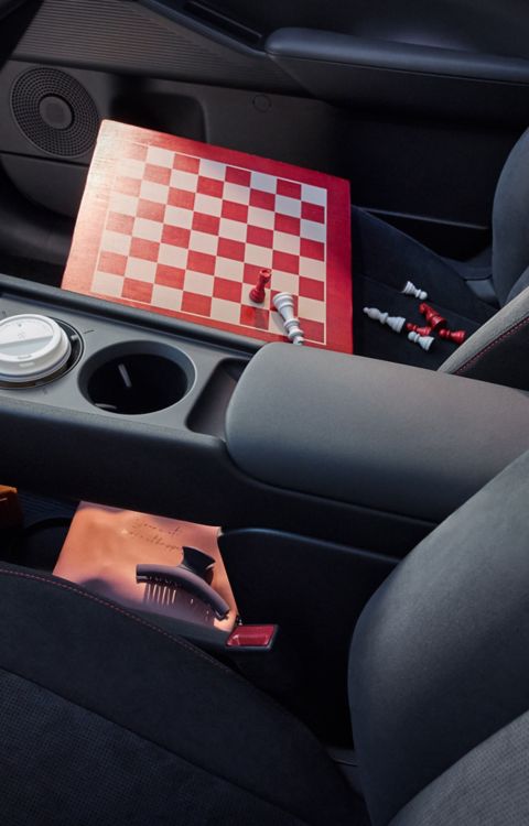 Console centrale de l'habitacle de la Hyundai IONIQ 3 avec un échiquier en bois sur le siège passager.