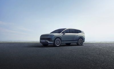 Vorderansicht des all-new Hyundai IONIQ 9 mit einer sonnigen Skyline im Hintergrund.