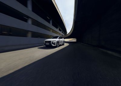 Un Hyundai TUCSON N Line blanc circulant entre des bâtiments.
