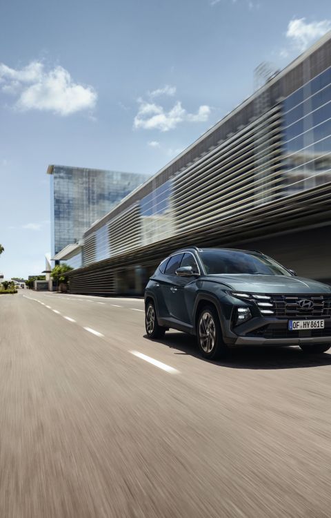 El Hyundai TUCSON circulando por una calle de la ciudad, con edificios modernos a la vista.