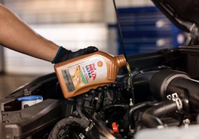 Hyundai KONA Elektrik SUV’un gün ışığı altında görüntüsü ve yolcu kapısına doğru yürüyen bir bir adam. 