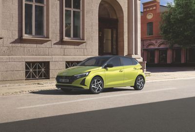 A young woman skateboarding in the street with a Hyundai i20 in the background.	